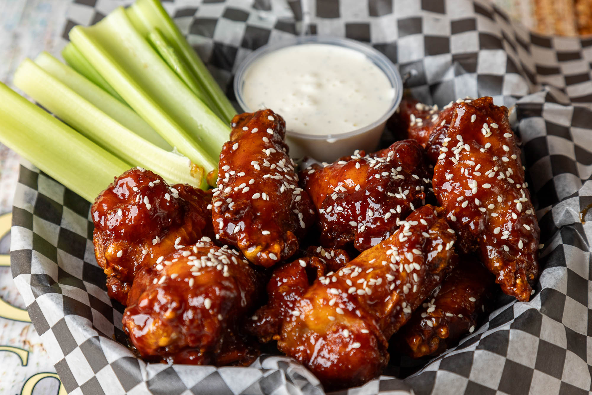 Glazed chicken wings with sesame seeds, celery sticks, and dipping sauce