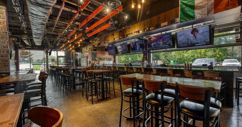 Interior with wooden tables, exposed ductwork and multiple TV's