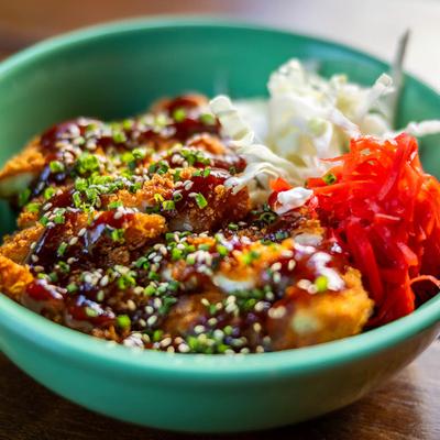 Breaded chicken cutlets with cabbage, sauce, and sesame seeds.