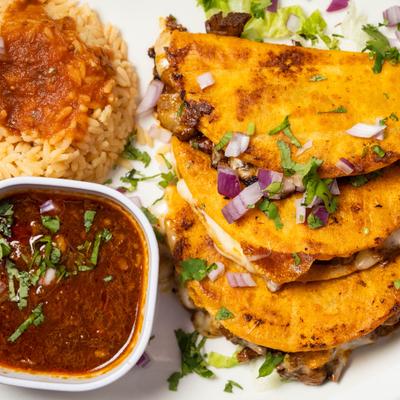 Quesabirria tacos filled with cheese and served with rich meat broth for dipping.