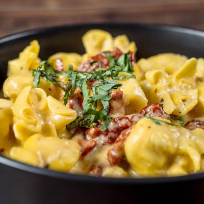 Sacchettini topped with crispy bacon bits and fresh green herbs.