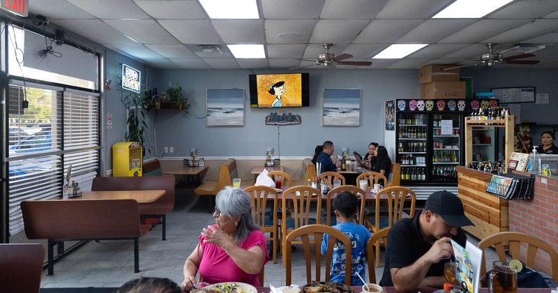 Diner area, tables, chairs, guests, tv screen above