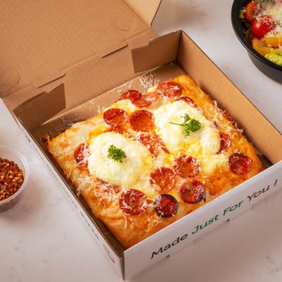 A square ricotta hot honey pizza inside a cardboard delivery box.