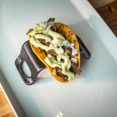 Cheeky chicken taco topped with raw diced onions and a drizzle of white sauce.