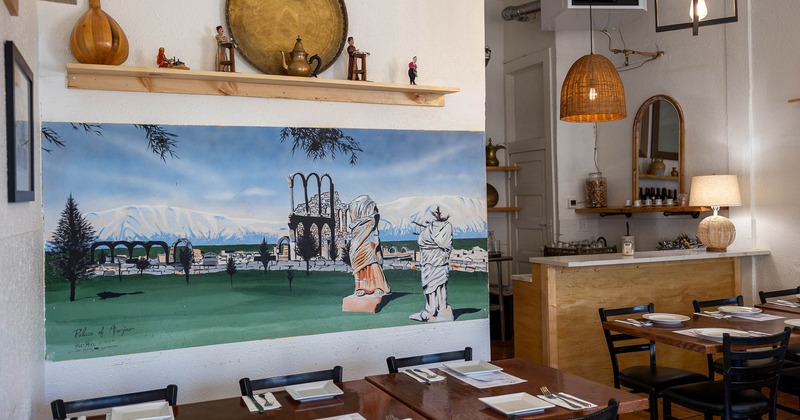 Interior, painting on the wall near tables set for guests