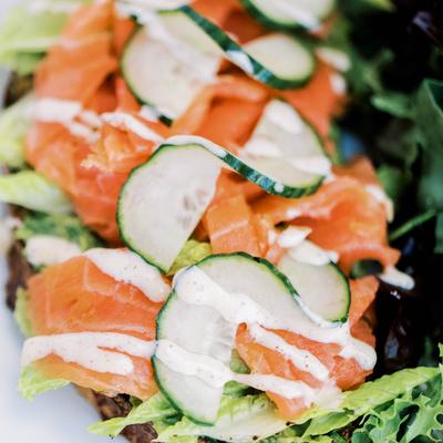 Avocado toast topped with smoked salmon, cucumbers, and aioli.