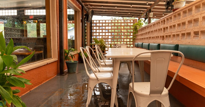 Outdoor dining area with a long white table and metal chairs