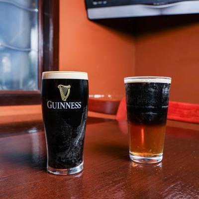 Stout beer served beside lighter ale on wooden counter.