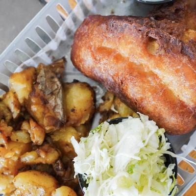 Fried fish with crispy roasted potatoes and a side of shredded cabbage.