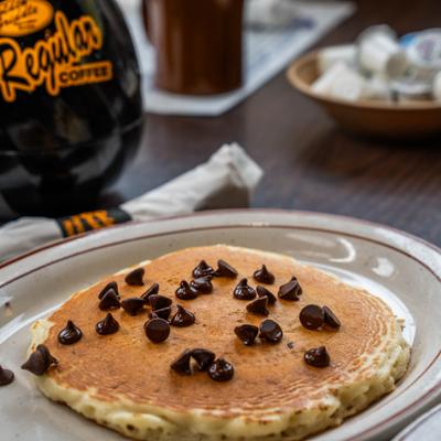 Buttermilk pancake topped with chocolate chips on a restaurant table.