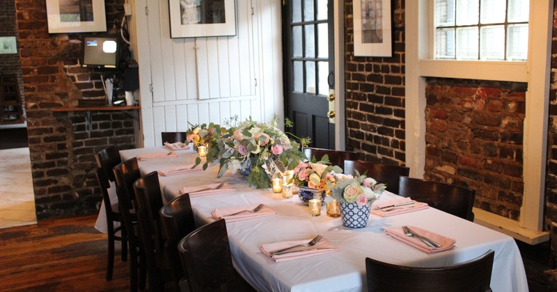 Interior with brick walls, artwork, and a set table with a floral centerpiece
