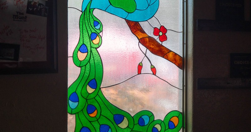 A table in front of a stained glass window with a picture of a peacock