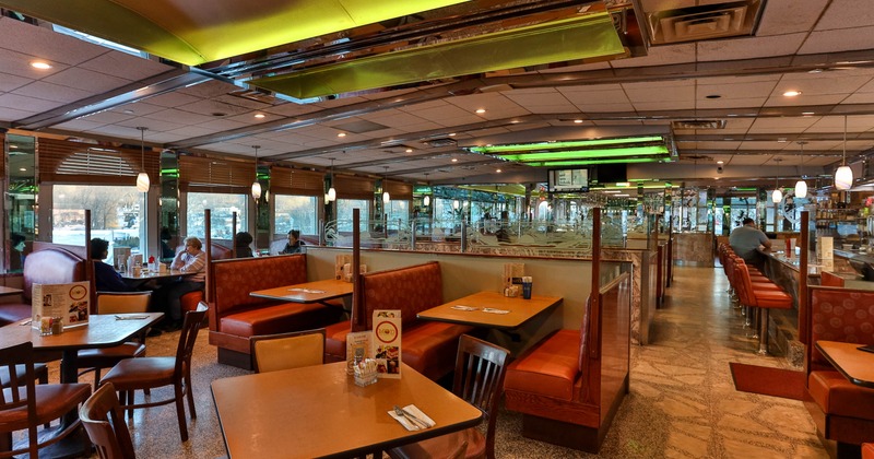 Interior of a classic diner with booths, tables, and a counter with red stools