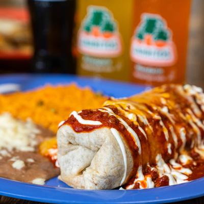 Burrito topped with sour cream and chili sauce, served with rice and beans.