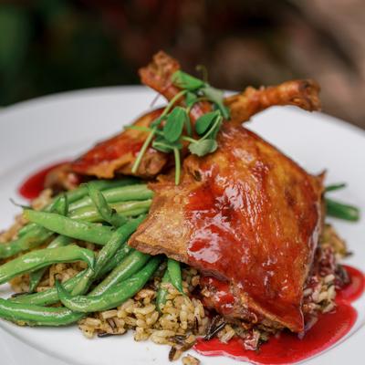 Roasted duck leg with green beans, rice, and red sauce