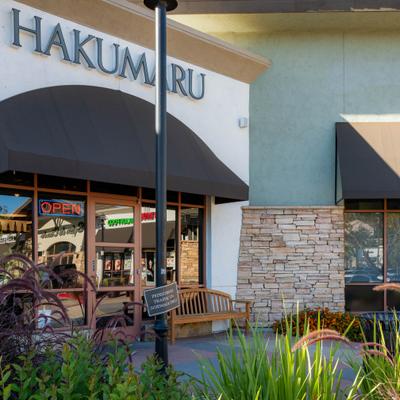 Hakumaru restaurant exterior with an Open sign and landscaped entrance.