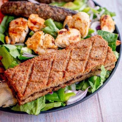 Mixed grill platter featuring kofta kebab, chicken skewers, kibbeh and hummus.