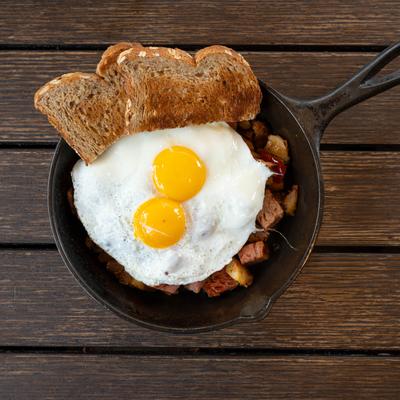 Corned beef hash topped with two fried eggs and served with toast.