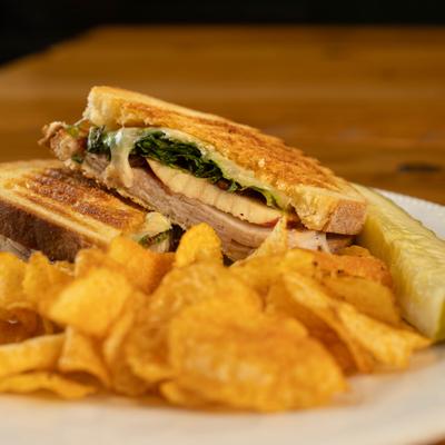 The Pilgrim sandwich served with chips and a pickle spear.