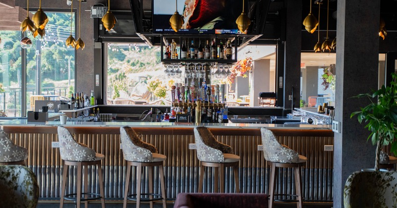A stylish bar interior with high bar stools and gold pendant lighting