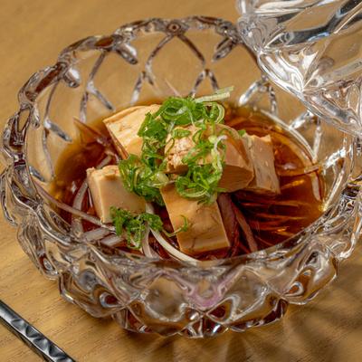 Monkfish liver served in a sauce and garnished with chopped green onions.