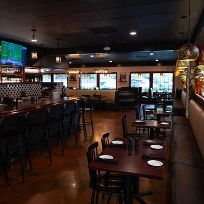 Dining area with a bar, wooden tables, and warm lighting.
