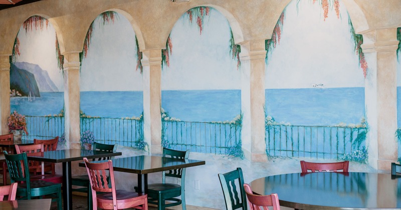 Tables by a wall decorated with a mural painting with seaside motifs
