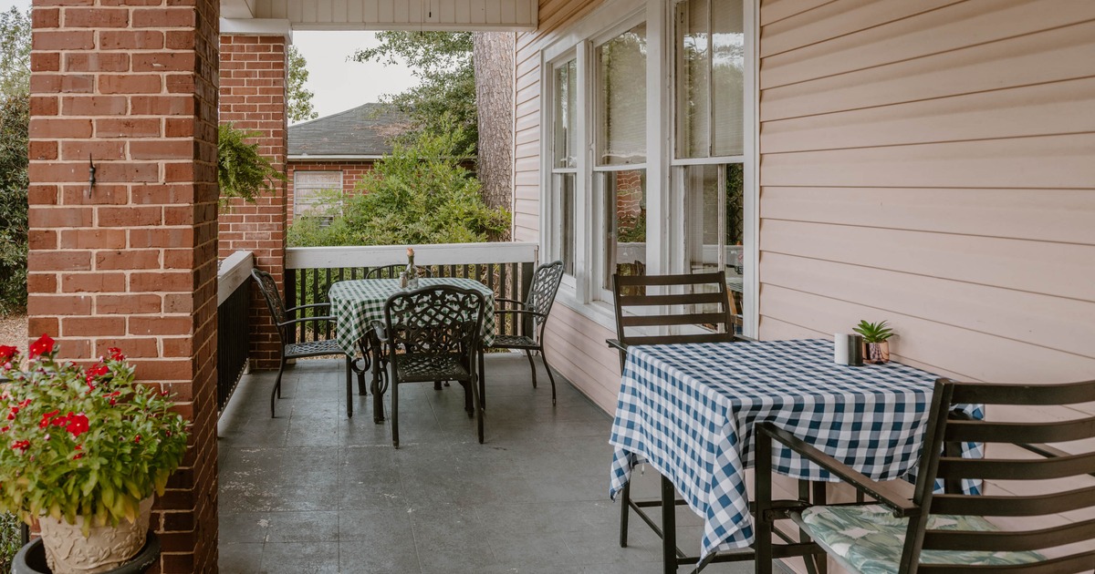Outdoor porch with tables set with checkered tablecloths and potted plants