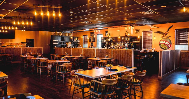 Interior, wide view, tables with tableware and chairs with bar in the background