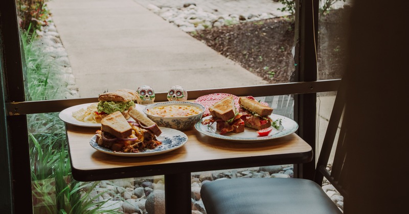 A table for two by a window, set with sandwich plates and a bowl of mac and cheese