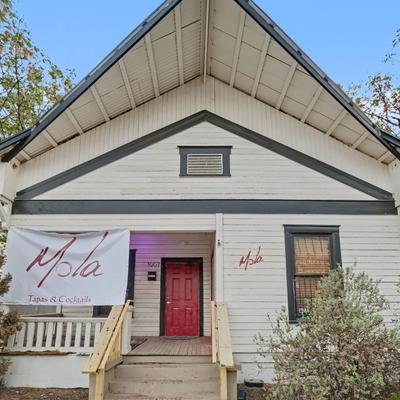 White restaurant exterior with red door and sign.