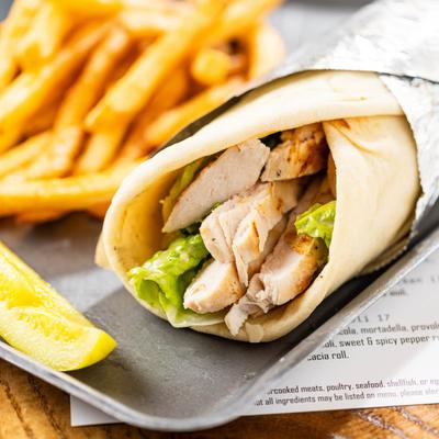 Grilled chicken wrap served with fries and a lemon wedge.