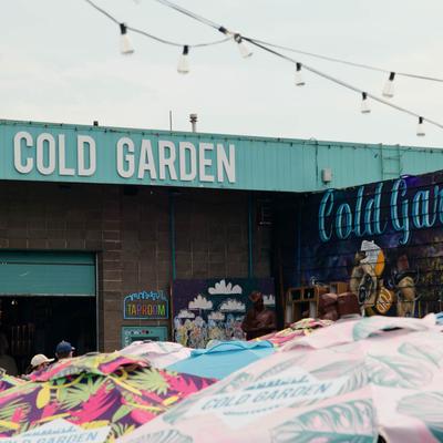 Cold Garden brewery exterior with colorful umbrellas and string lights.