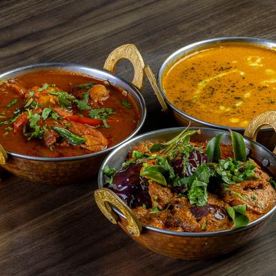 Three curries arranged in metal bowls.