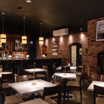 Elegant bar and lounge area with marble-top tables, a brick interior and a warm-lit ambiance.