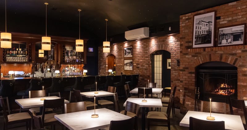 Elegant bar and lounge area with marble-top tables, a brick interior and a warm-lit ambiance