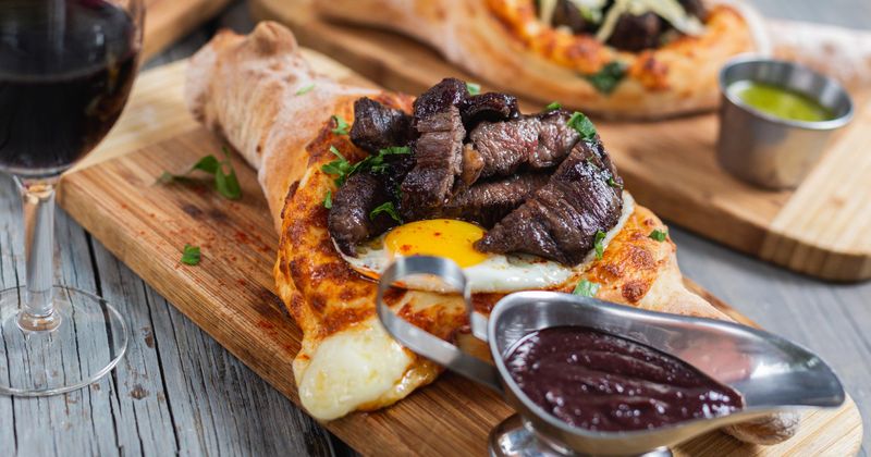 Georgian steak and eggs cheese boat served with dark sauce and red wine