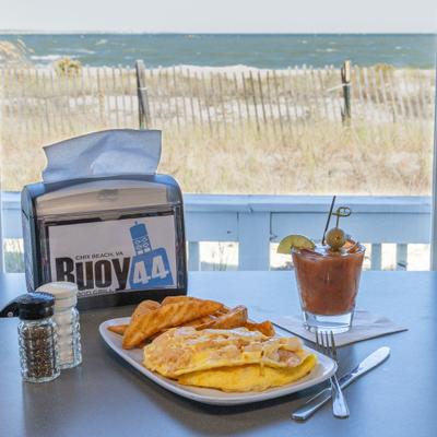 Shrimp and crab omelet served with potato wedges and a cocktail.