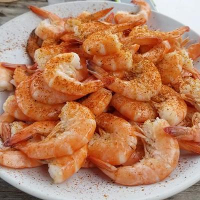 Steamed shrimp seasoned and served on white plate.