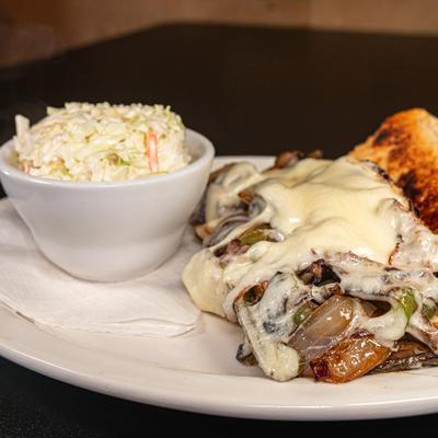 Steak Philly sandwich topped with melted cheese and served with coleslaw.