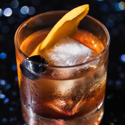 Old Fashioned cocktail garnished with an orange peel and a maraschino cherry.