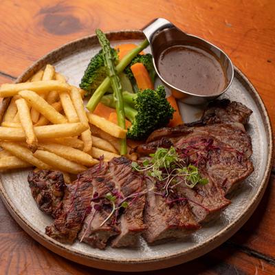 Steak Frites served with vegetables and sauce on the side.