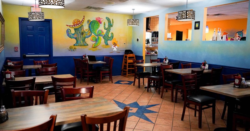 Interior, seating area with tables, chairs and a decorated wall