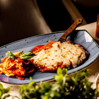 Chicken parmigiana served with pasta on the side.