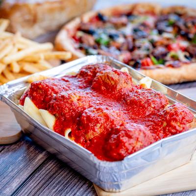 Meatball Parmesan Pasta topped with marinara, fries and veggie pizza in the background.
