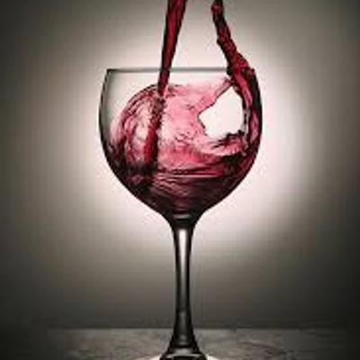 Wine being poured into a glass on a table with grey gradient background.