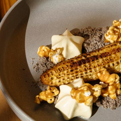 Grilled baby corn with caramel popcorn, cream dollops, and crumb topping.