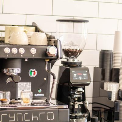 Black espresso machine and grinder on a coffee shop counter.
