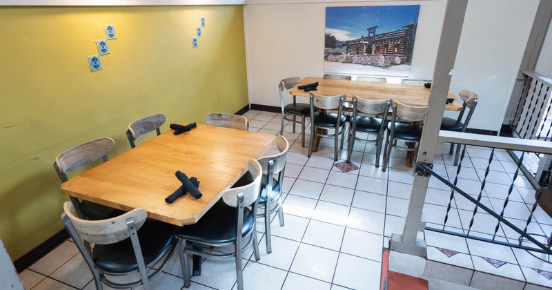 Restaurant dining area with wooden tables, metal chairs, and decorative tiles on floor and walls