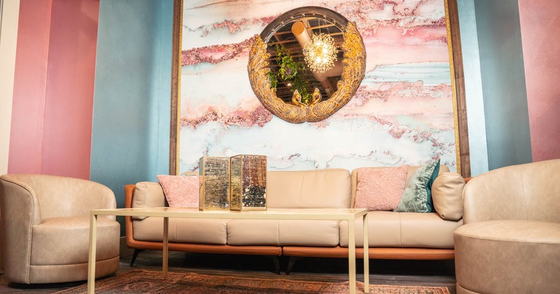 Interior, two chairs and a large sofa, abstract painted wall, large round decorated mirror